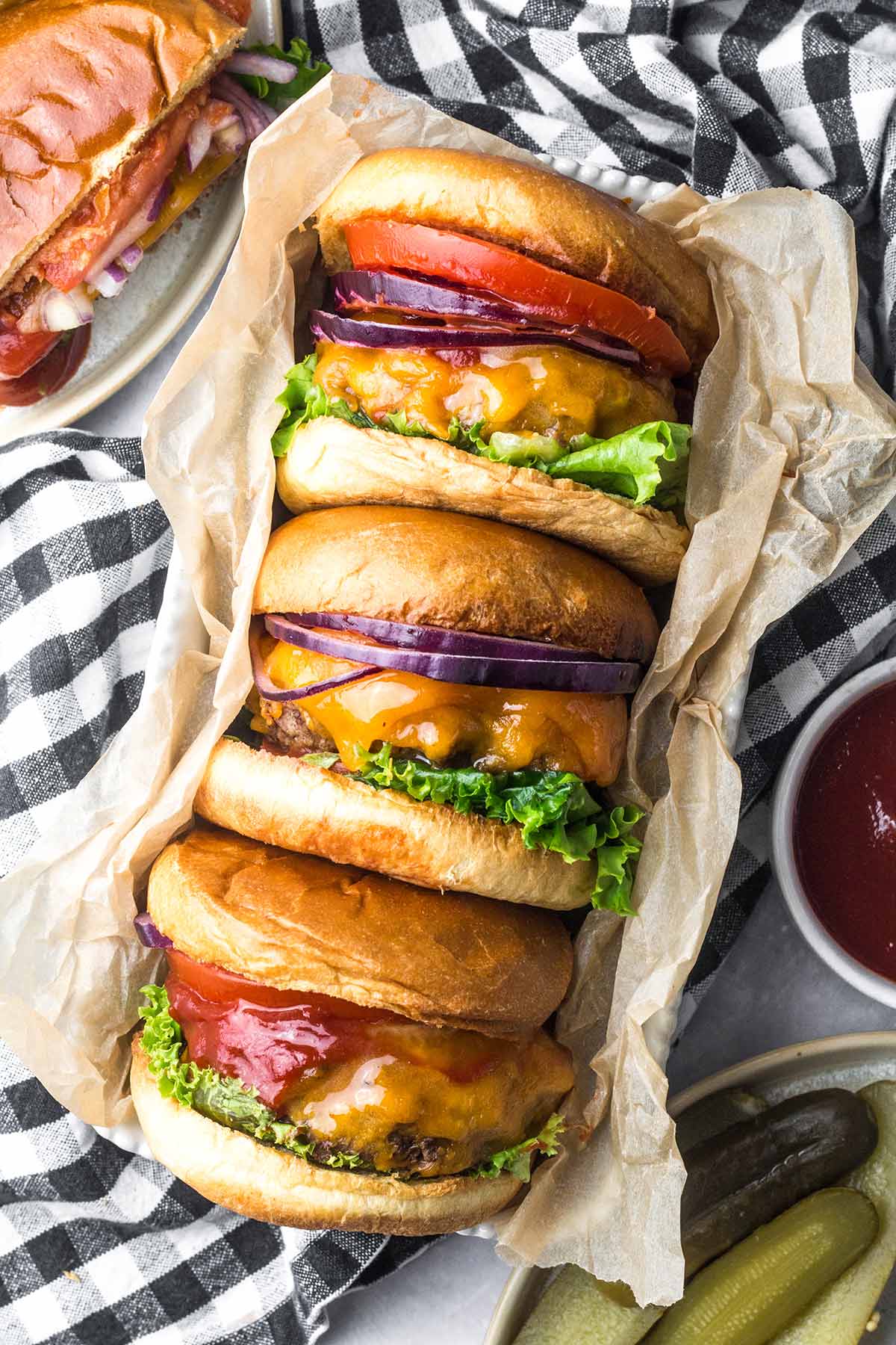 Three cheeseburgers with lettuce, tomato and onion. 