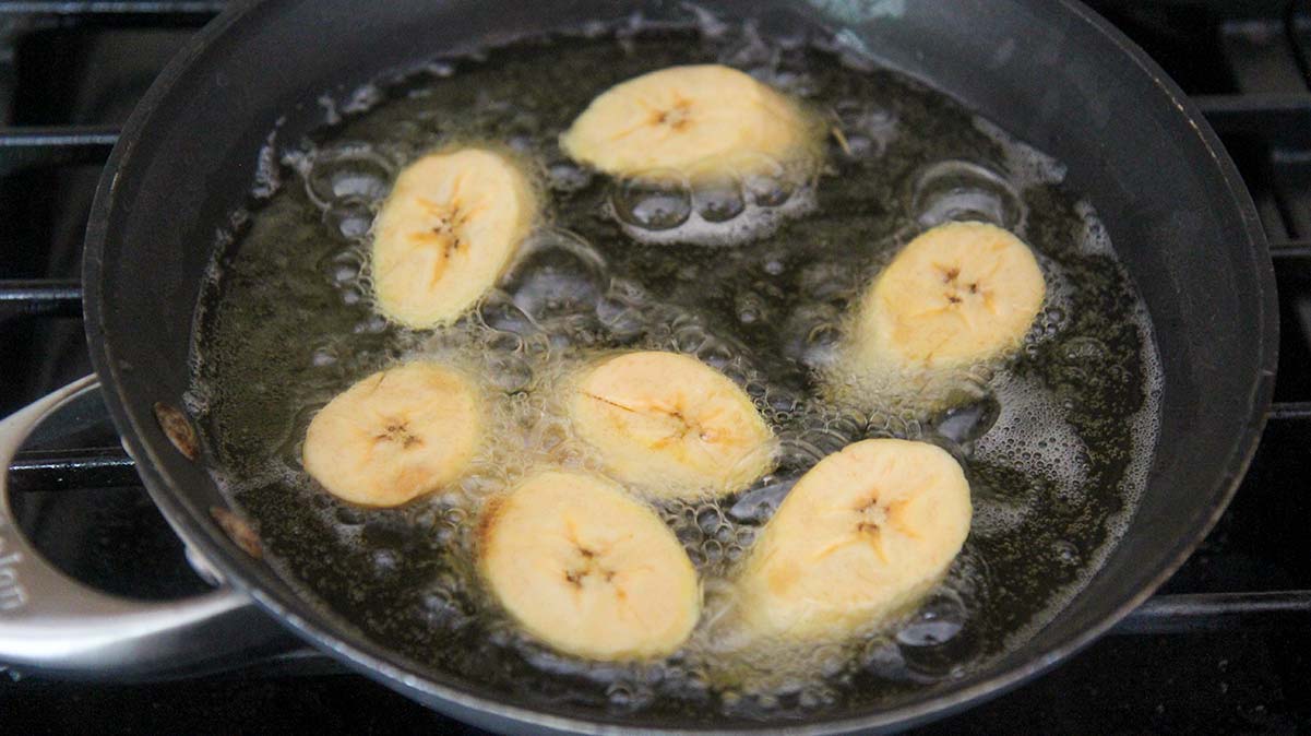 seven plantain slices frying in oil. 