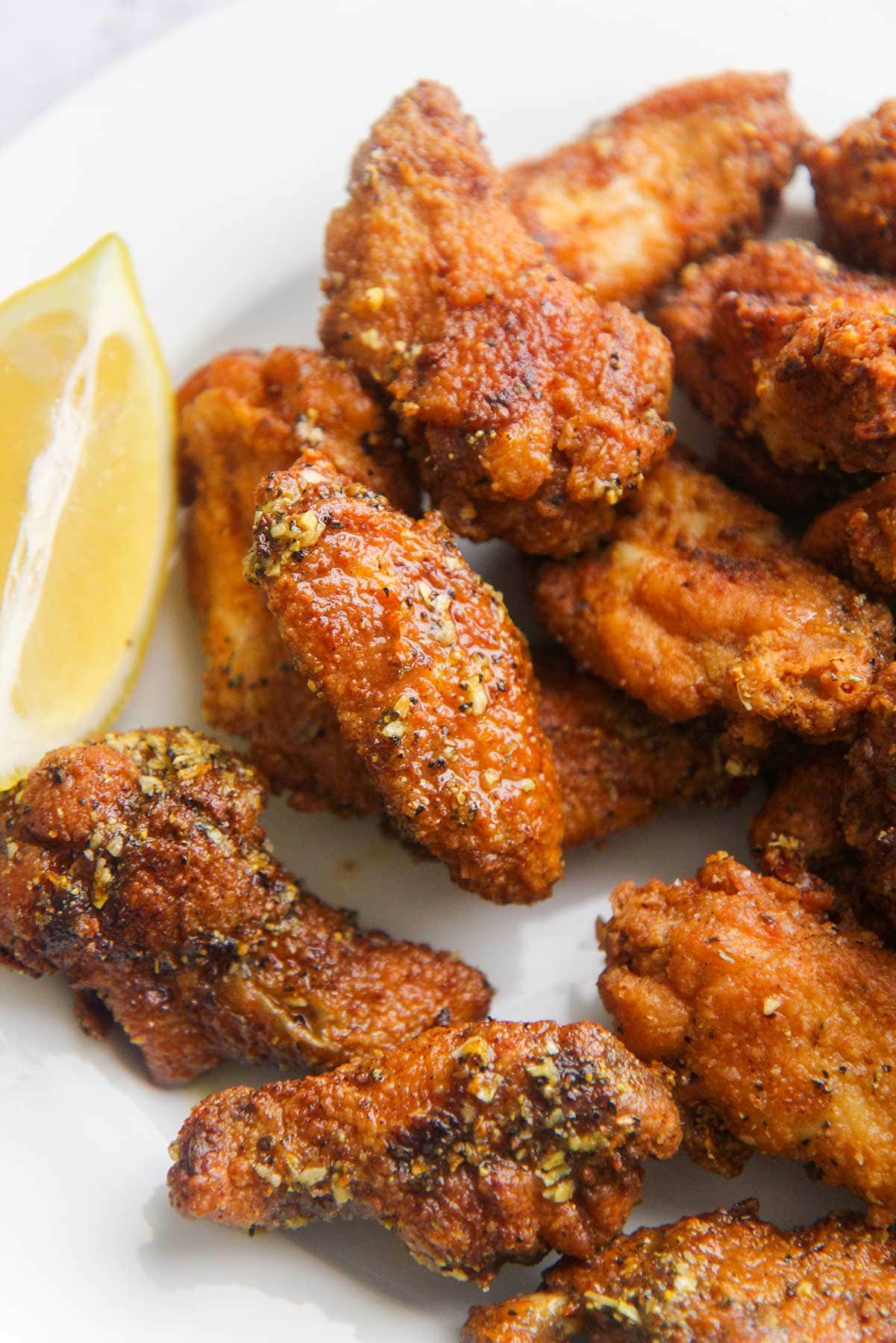 bone-in fried chicken wings with lemon wedges up close. 