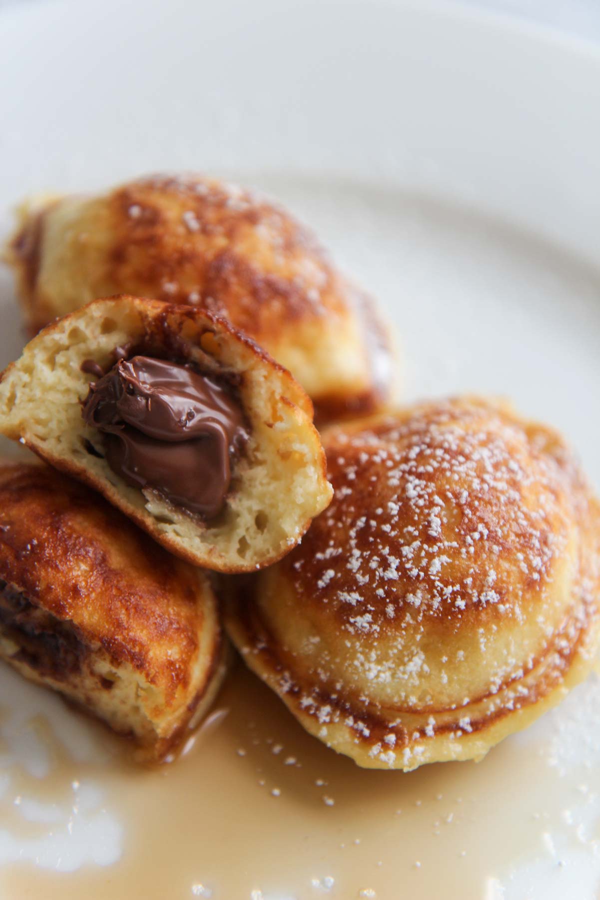 Nutella stuffed pancakes up close with powdered sugar on top. 