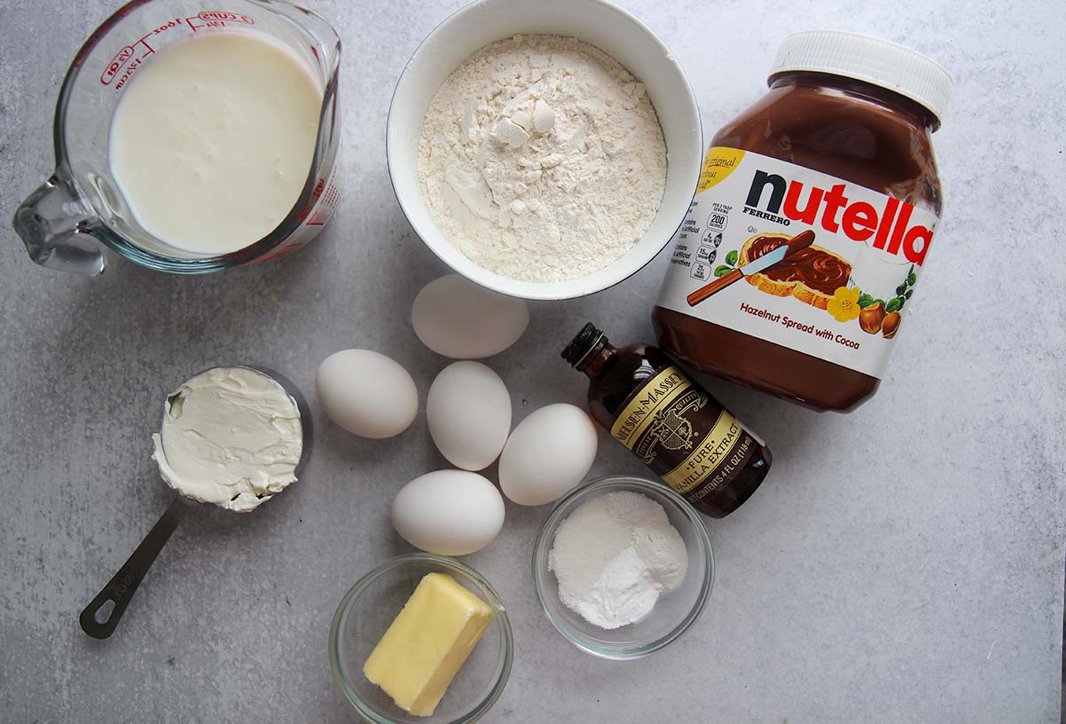 Ingredients to make Nutella stuffed Danish pancakes. Eggs, buttermilk, butter, Nutella, flour, sour cream, and vanilla extract. 