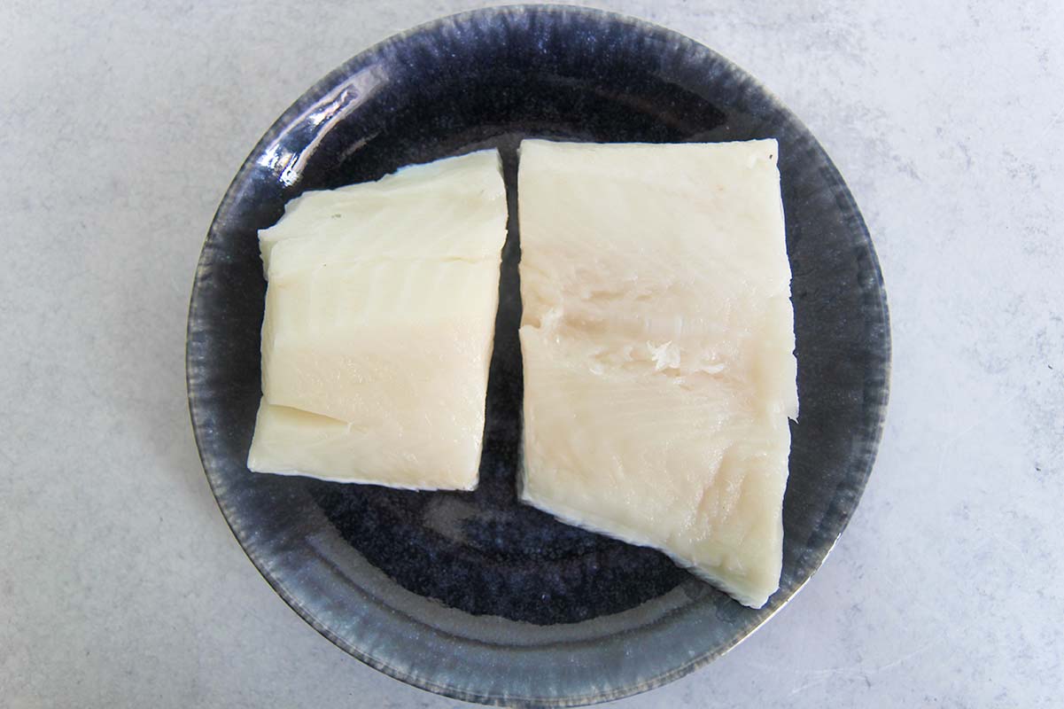 Two pieces of uncooked Chilean sea bass on a plate. 