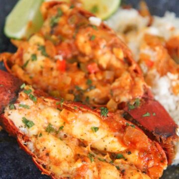 enchilado de langosta on a blue plate with rice and lime wedges.