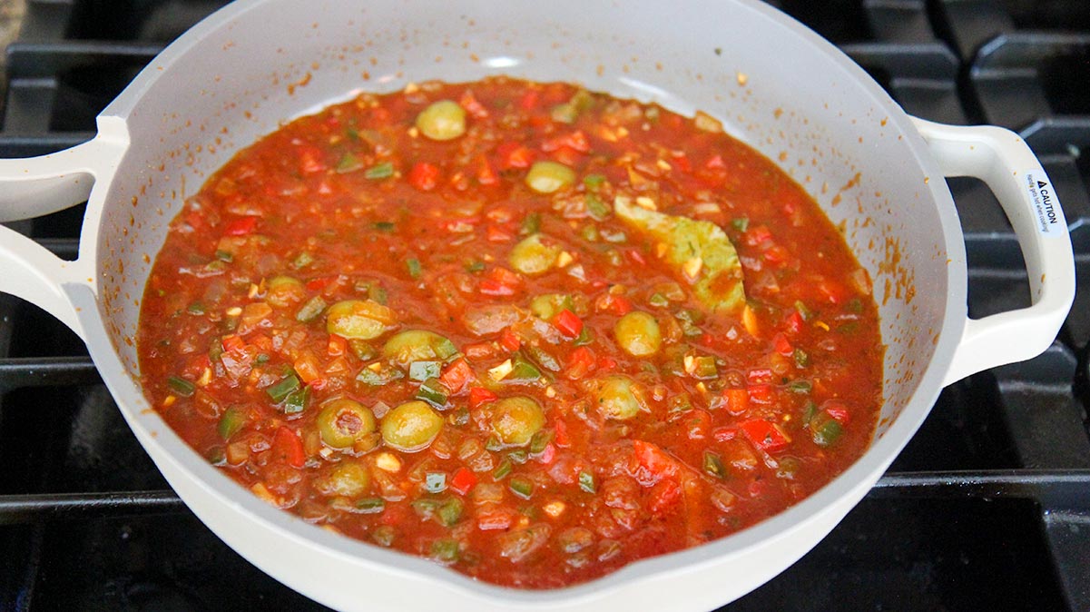 Creole sauce in a skillet cooking on the stovetop. 