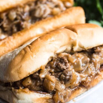 Two Philly cheesesteak sandwiches up close.