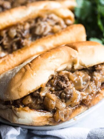 Two Philly cheesesteak sandwiches up close.