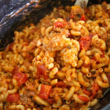 crockpot cheesy beef goulash with a wooden spoon.