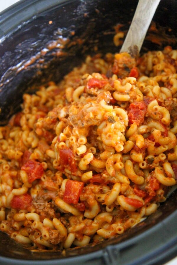 crockpot cheesy beef goulash with a wooden spoon.