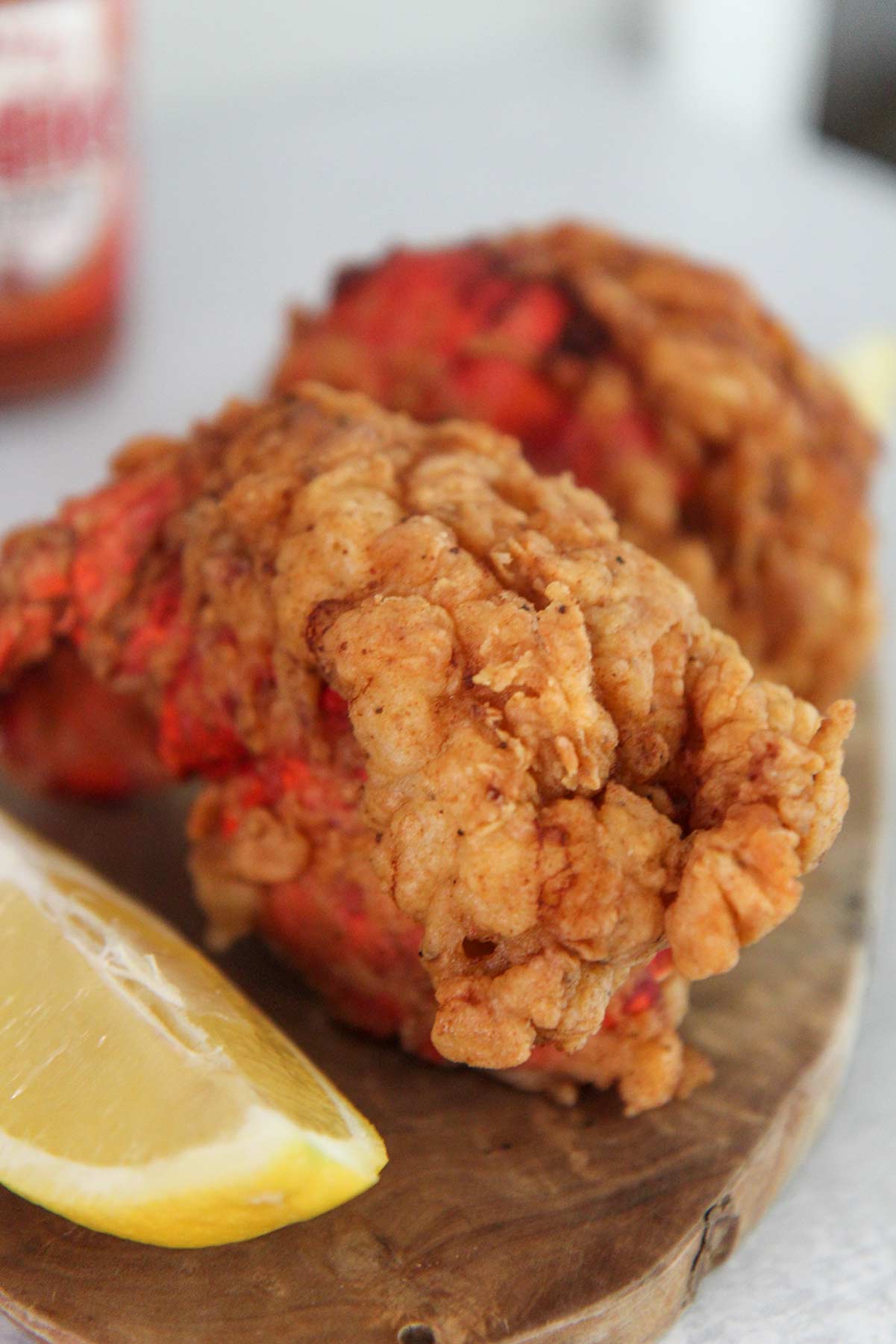 Two fried lobster tails up close with a lemon wedge on the side.
