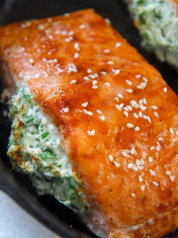 spinach stuffed salmon in a cast iron skillet.