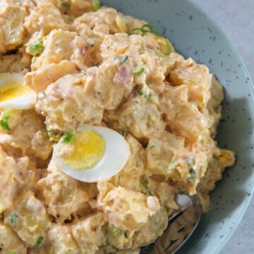 Southern potato salad in a blue plate with a spoon.