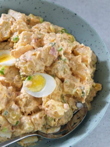 Southern potato salad in a blue plate with a spoon.