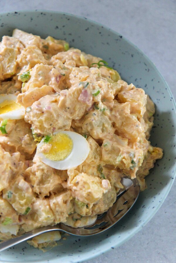 Southern potato salad in a blue plate with a spoon.