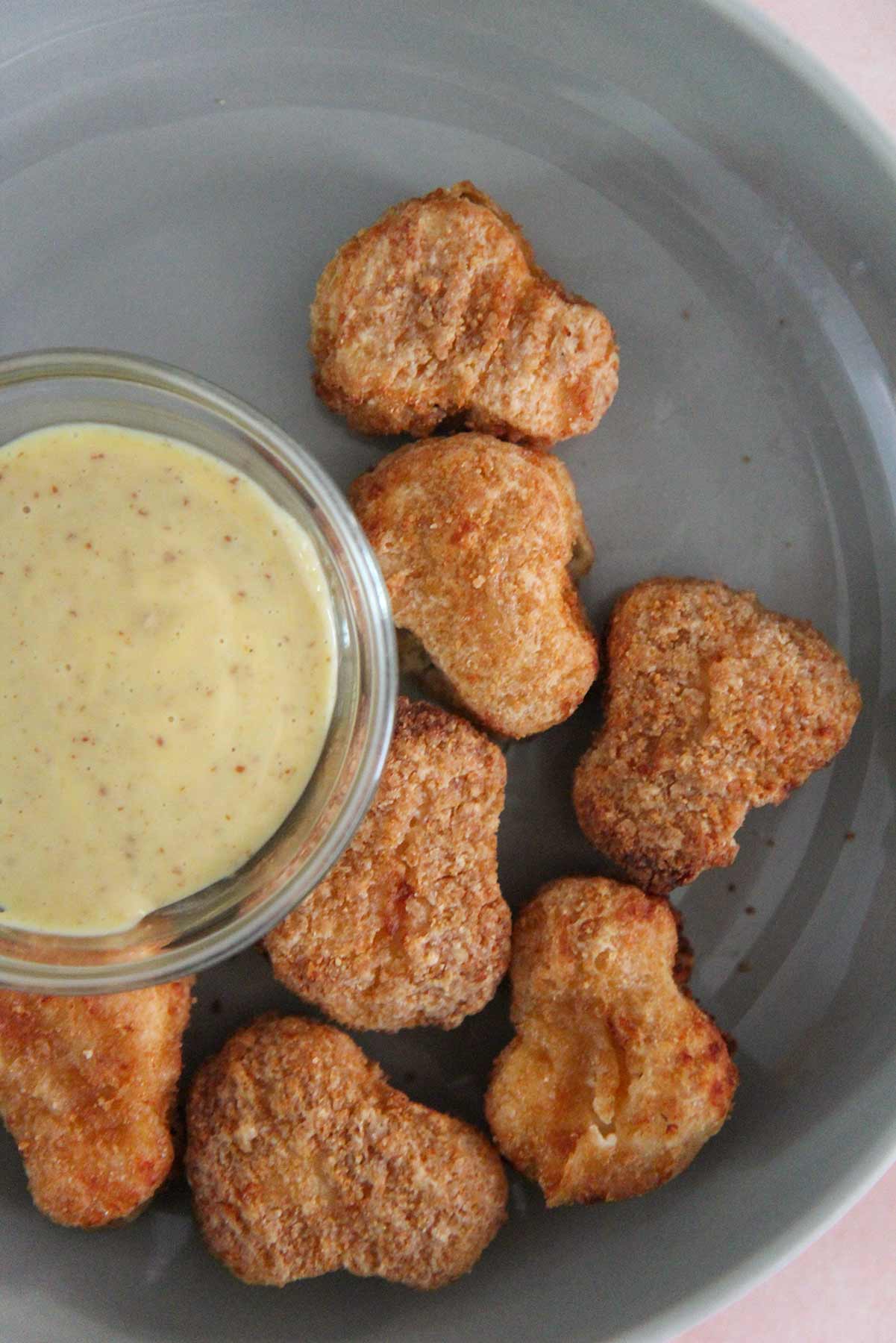 cooked chicken nuggets with sauce on the side. 