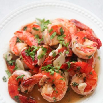 camarones al ajillo on a white plate with cilantro on top.