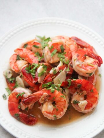 camarones al ajillo on a white plate with cilantro on top.