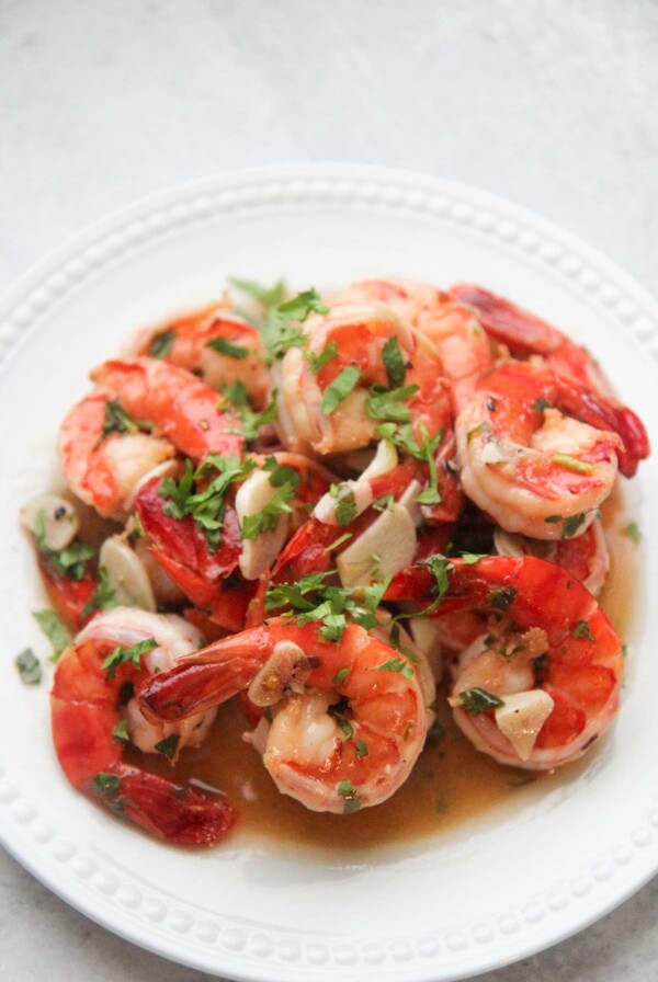 camarones al ajillo on a white plate with cilantro on top.