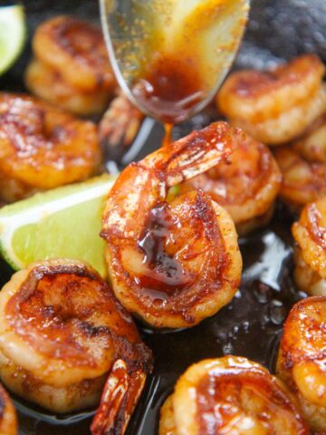 honey chili lime shrimp up close with a spoon drizzling sauce on top.