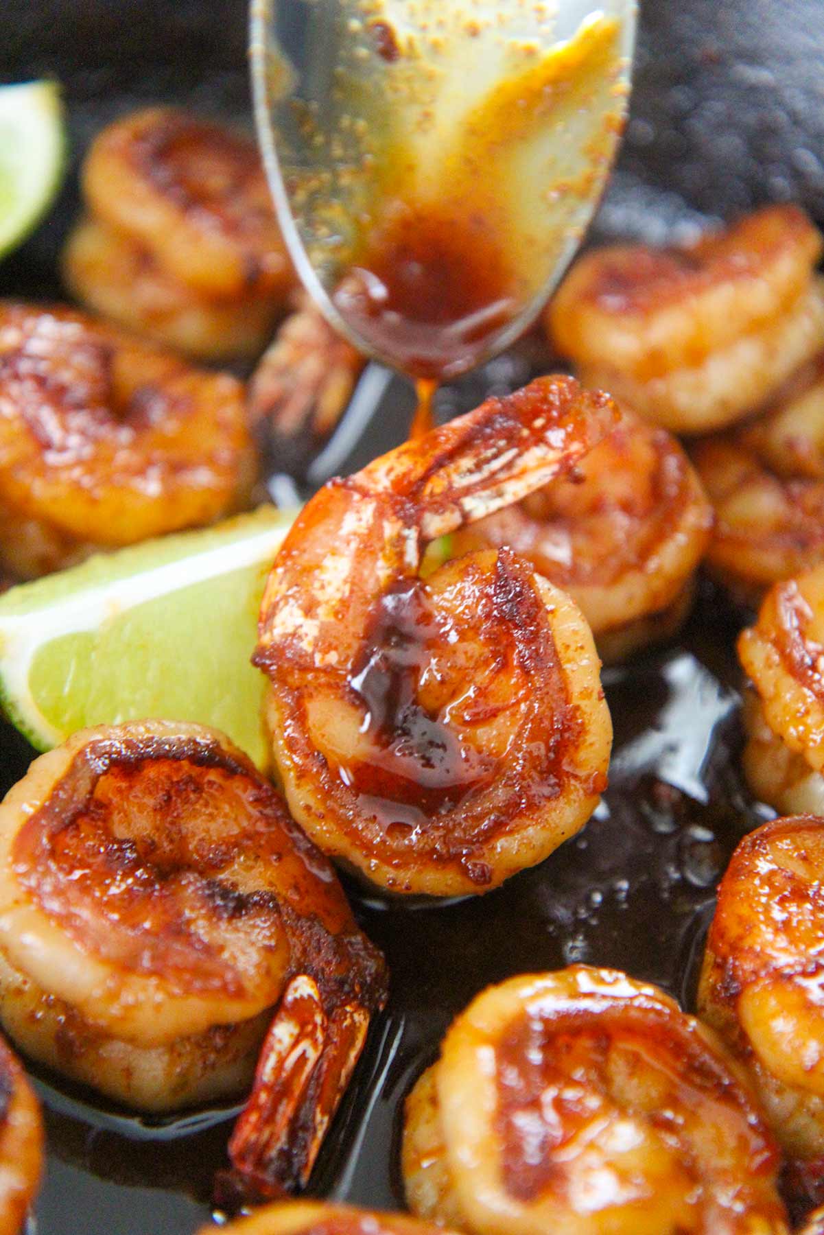honey chili lime shrimp up close with a spoon drizzling sauce on top.