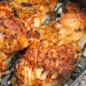 two cooked Chilean sea bass fillets in an air fryer basket.