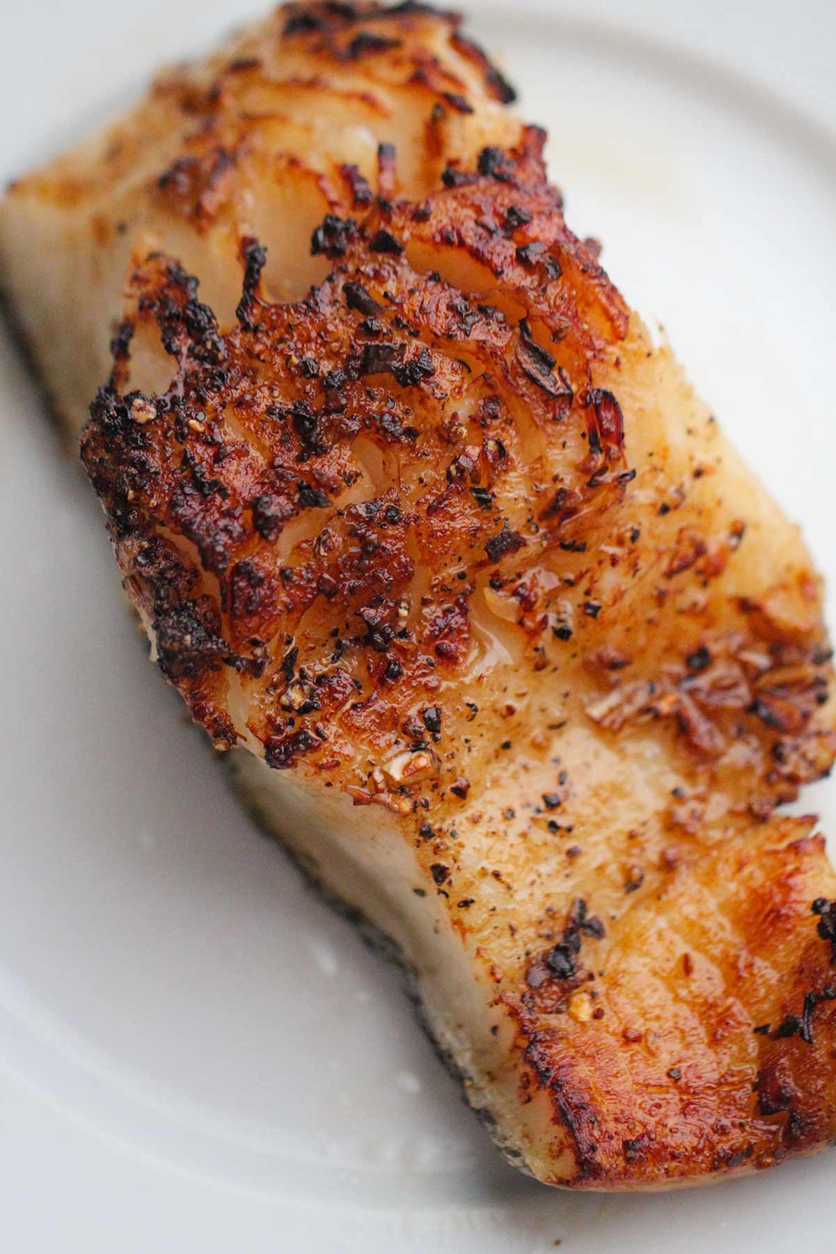 Air fryer honey Chilean sea bass on a white plate up close. 