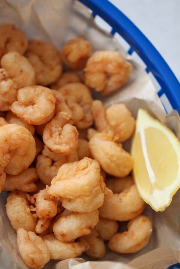 popcorn shrimp in a blue basket with a lemon wedge on the side.