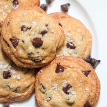 five brown butter chocolate chip cookies on a plate.