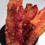 candied bacon strips in a cup.