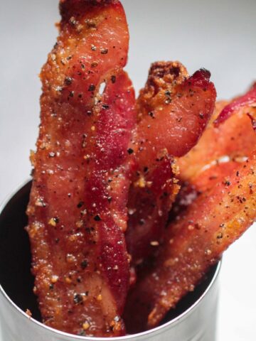 candied bacon strips in a cup.