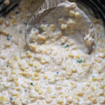 slow cooker creamed corn with a wooden spoon.