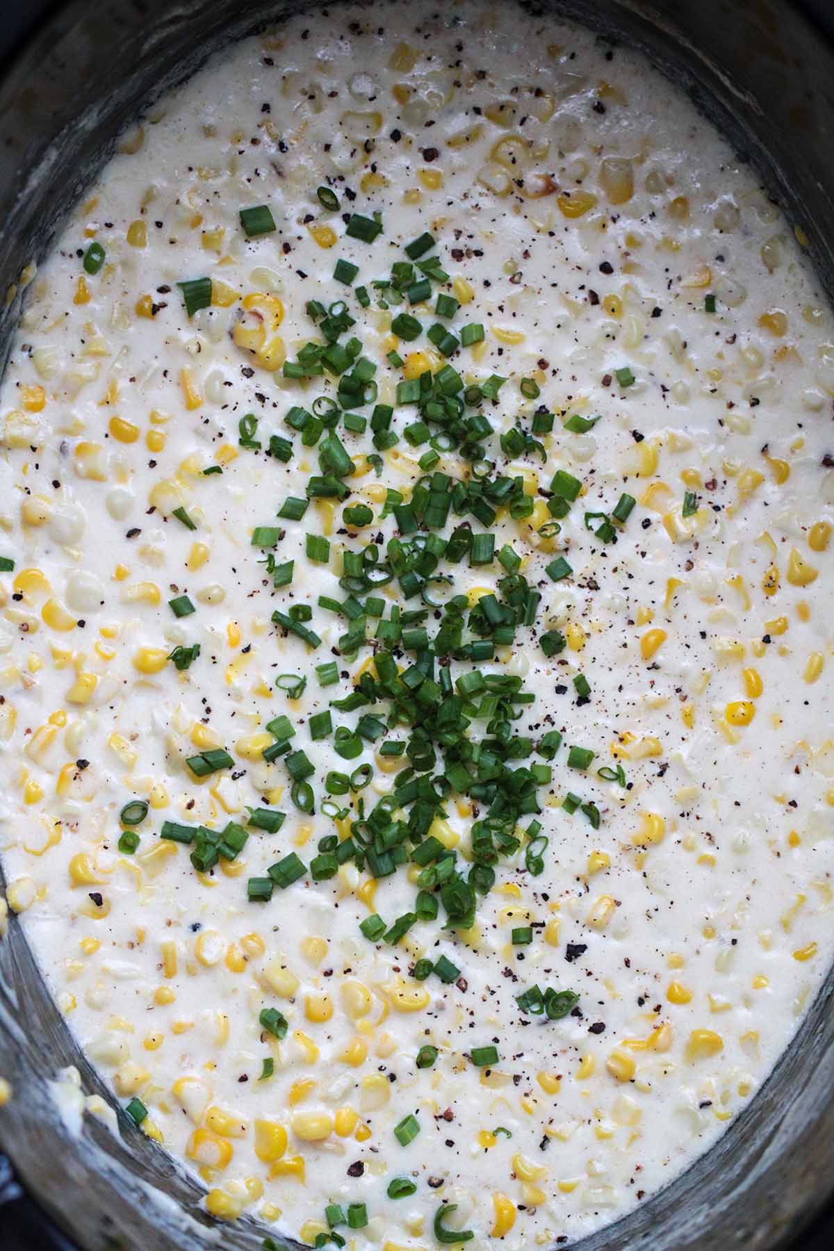 slow cooker creamed corn with fresh chives on top.