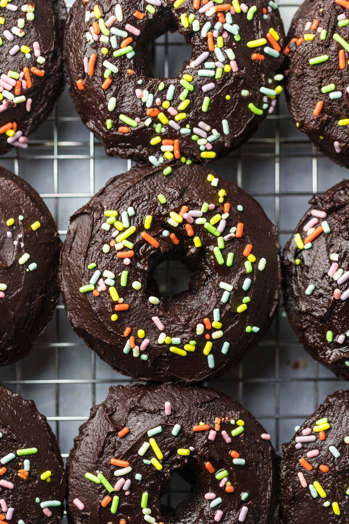 baked chocolate donuts with sprinkles up close. 