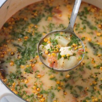 caldo de queso in a large white dutch oven with a ladle.