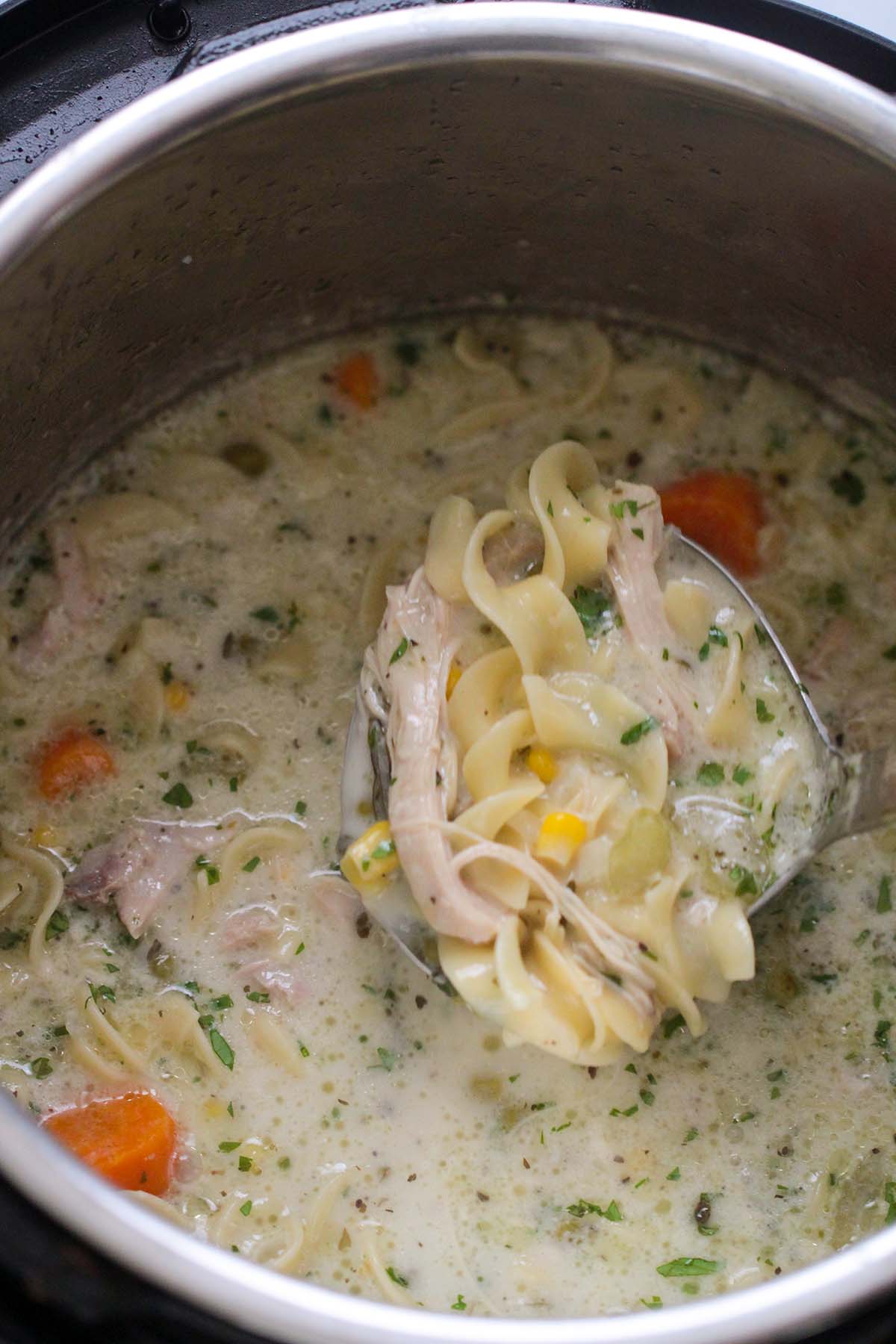 creamy chicken noodle soup in the instant pot with a ladle. 