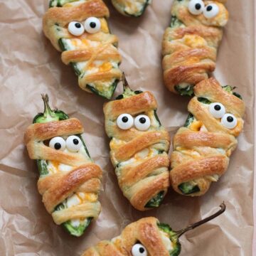 mummy jalapeno poppers on parchment paper.