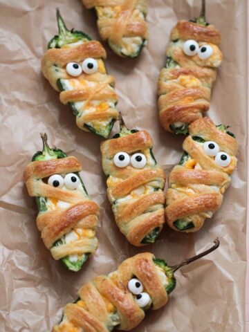 mummy jalapeno poppers on parchment paper.