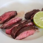 air fryer carne asada on a white plate with lime on the side.