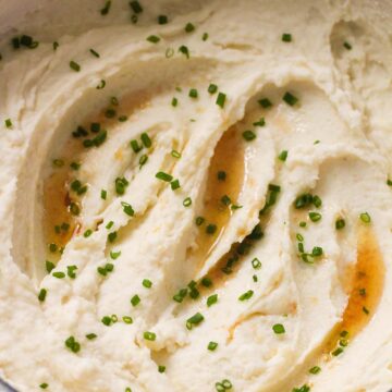 browned butter mashed potatoes in a dutch oven with chives on top.