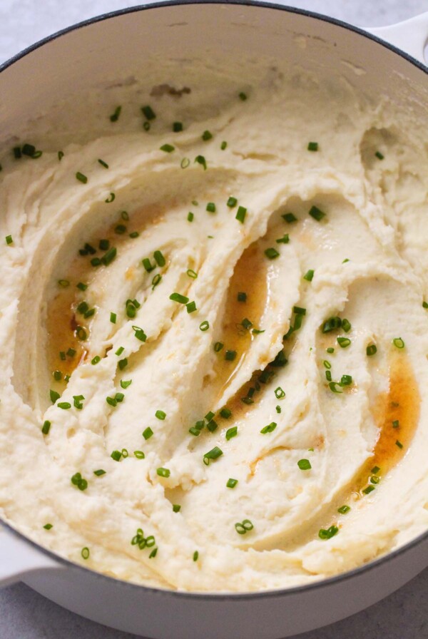 browned butter mashed potatoes in a dutch oven with chives on top.