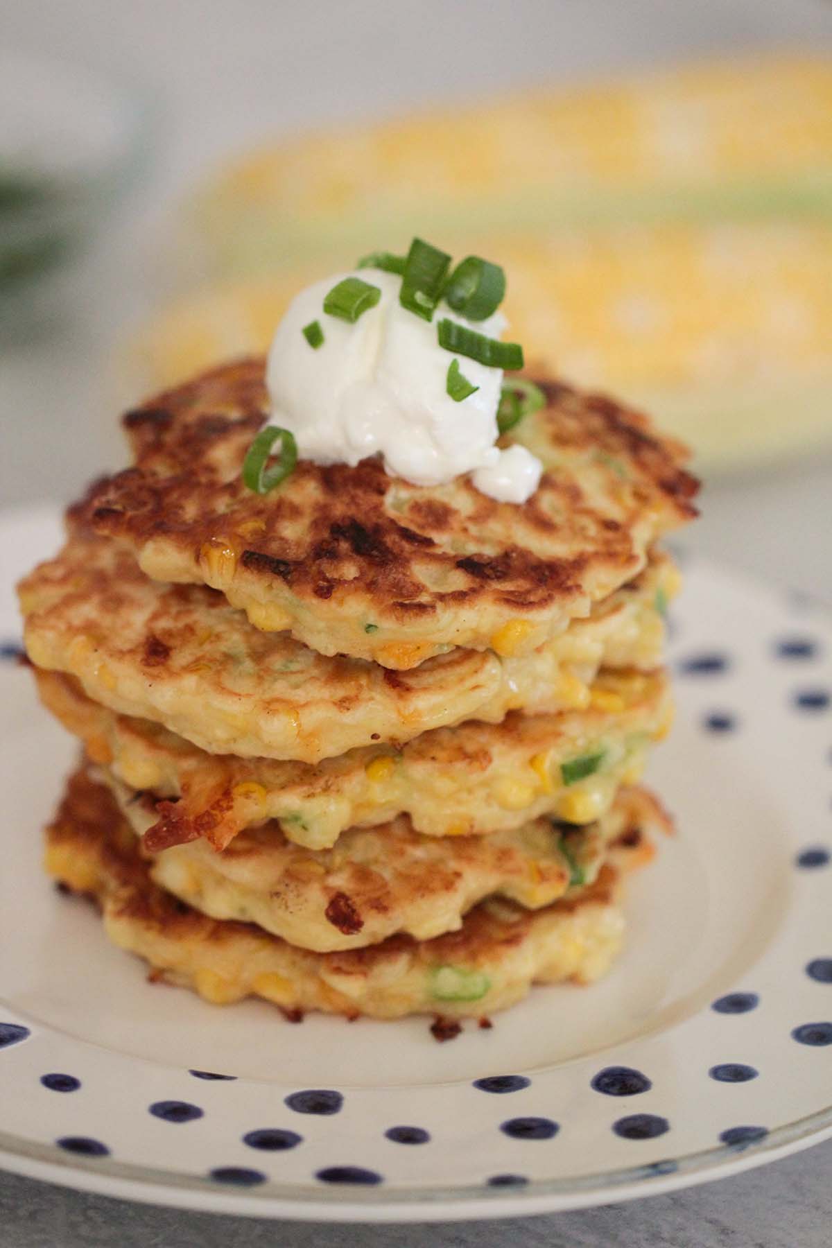 five corn fritters with sour cream and scallion on top. 