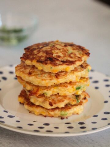 corn fritters stacked on a plate.