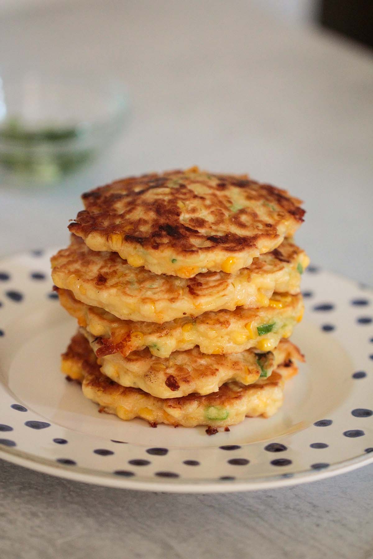 five corn fritters on a plate. 