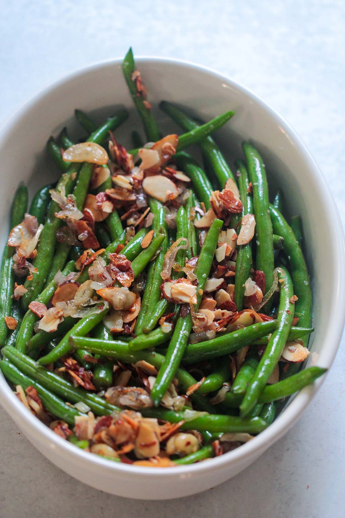 green beans almondine in a white dish.