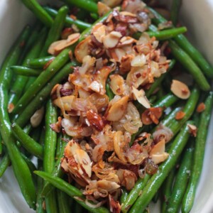 green beans almondine in a white dish up close.