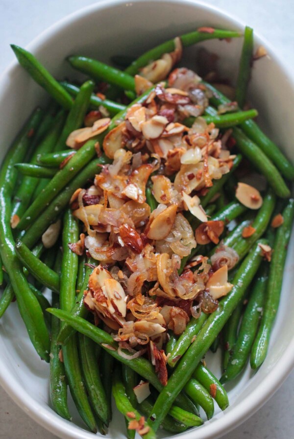 green beans almondine in a white dish up close.