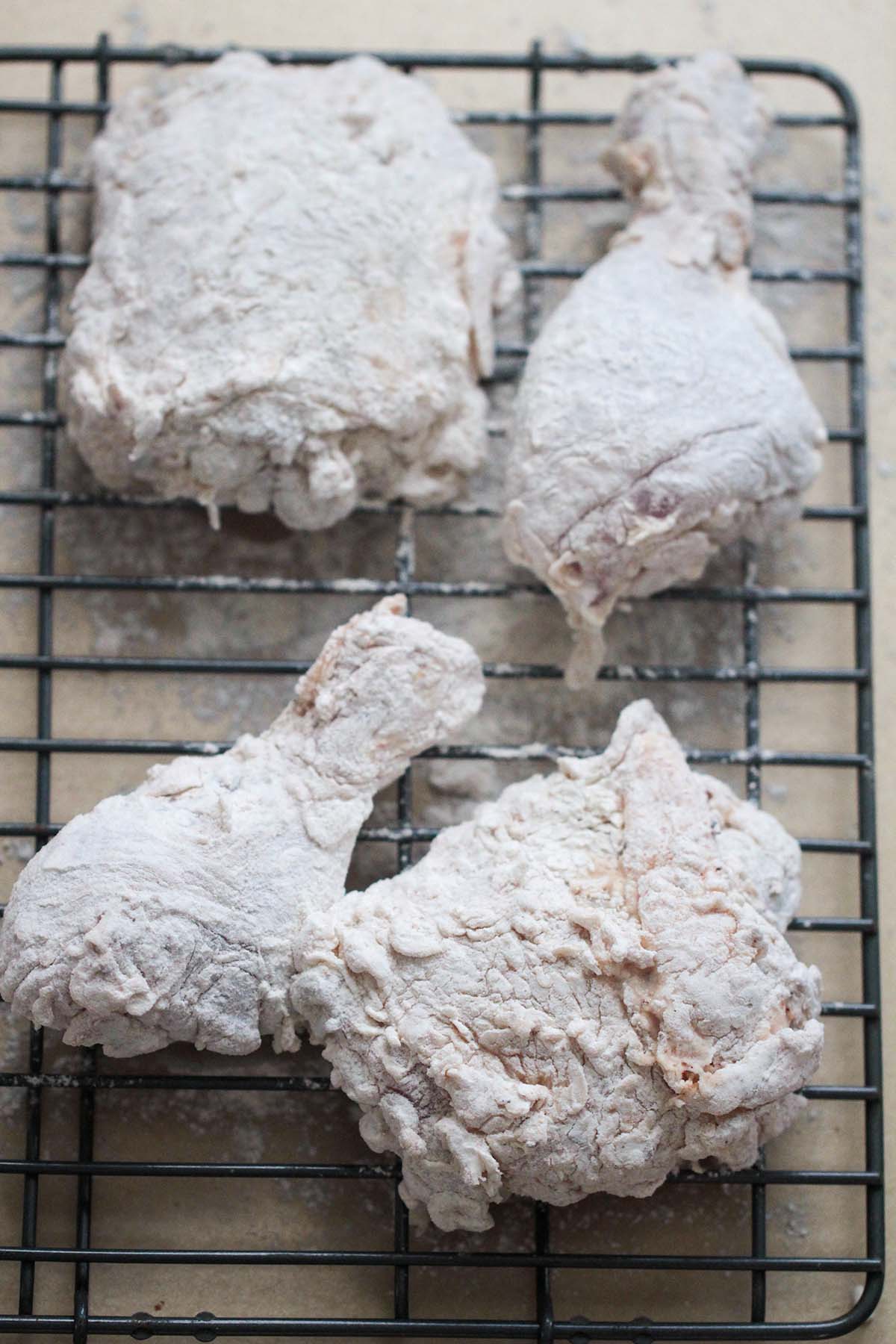 flour coated chicken thighs and chicken legs on a wire rack. 