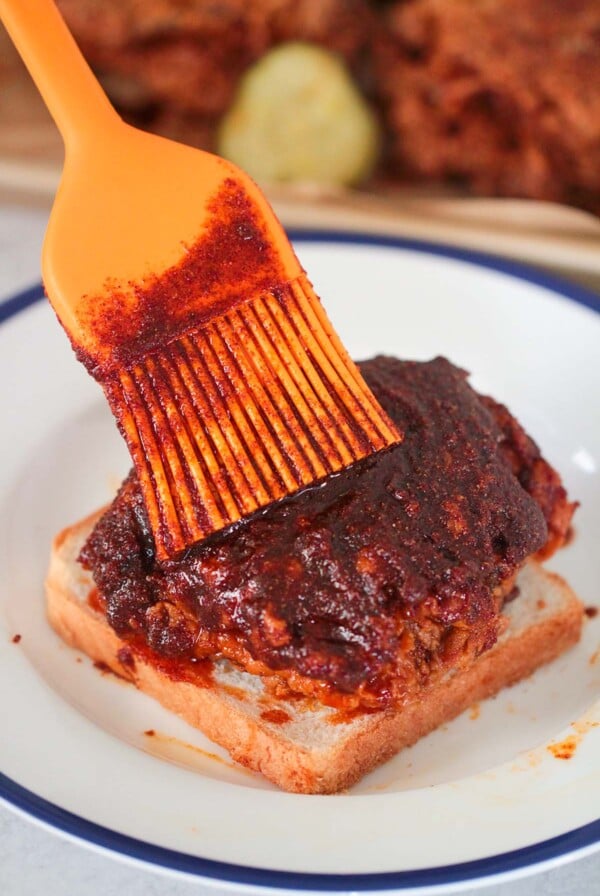 Nashville hot chicken on a slice of white bread and an orange brush.