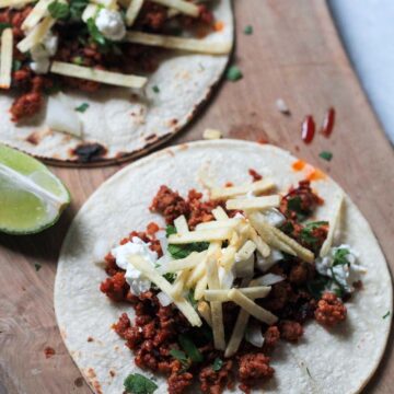 two chorizo tacos on a wooden board.