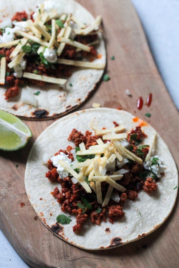 two chorizo tacos on a wooden board.
