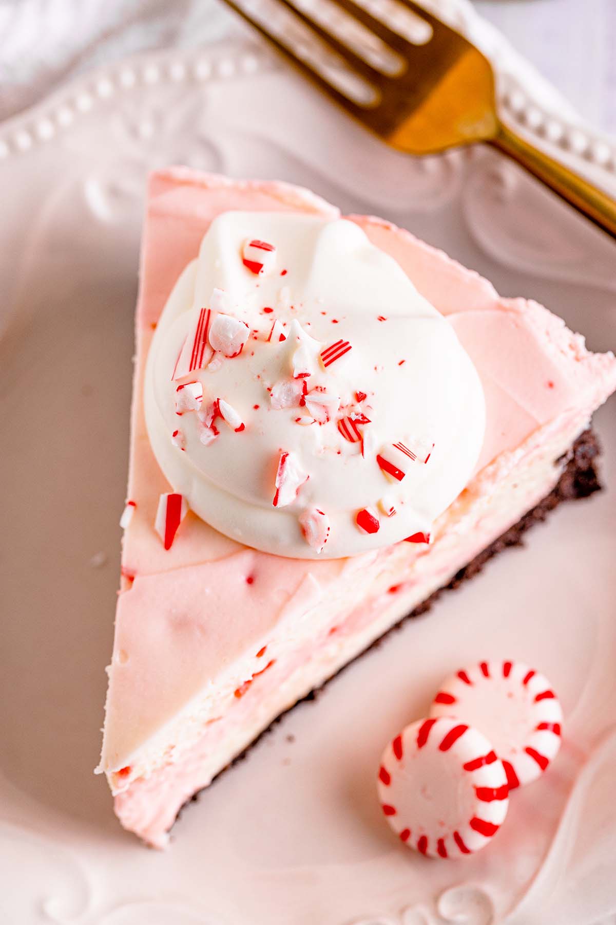 pink cheesecake with whipped cream on top and peppermint candies. 